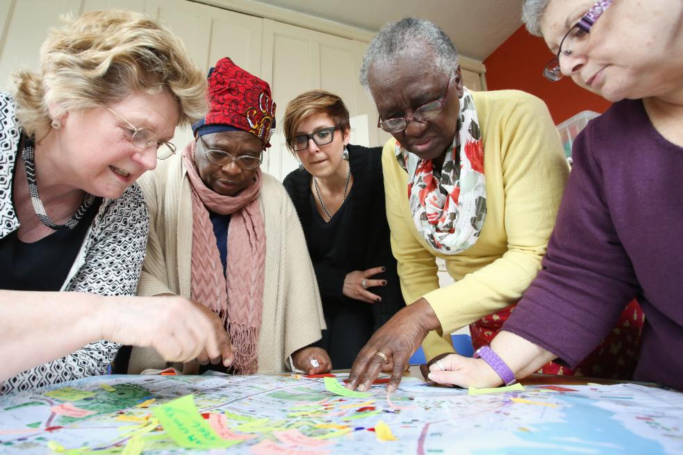 A group of people of various ages looking down at a map on a table