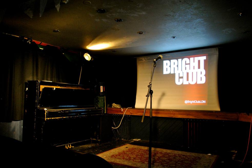 Bright club on projector screen behind microphone and piano