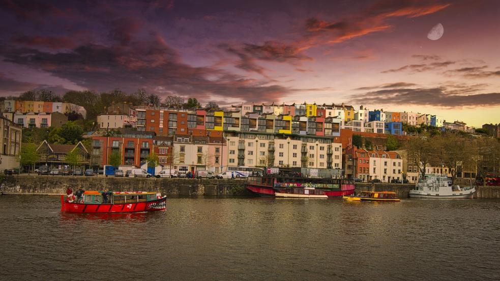 View of colourful buildings in Bristol with a boat on the river in the forefront