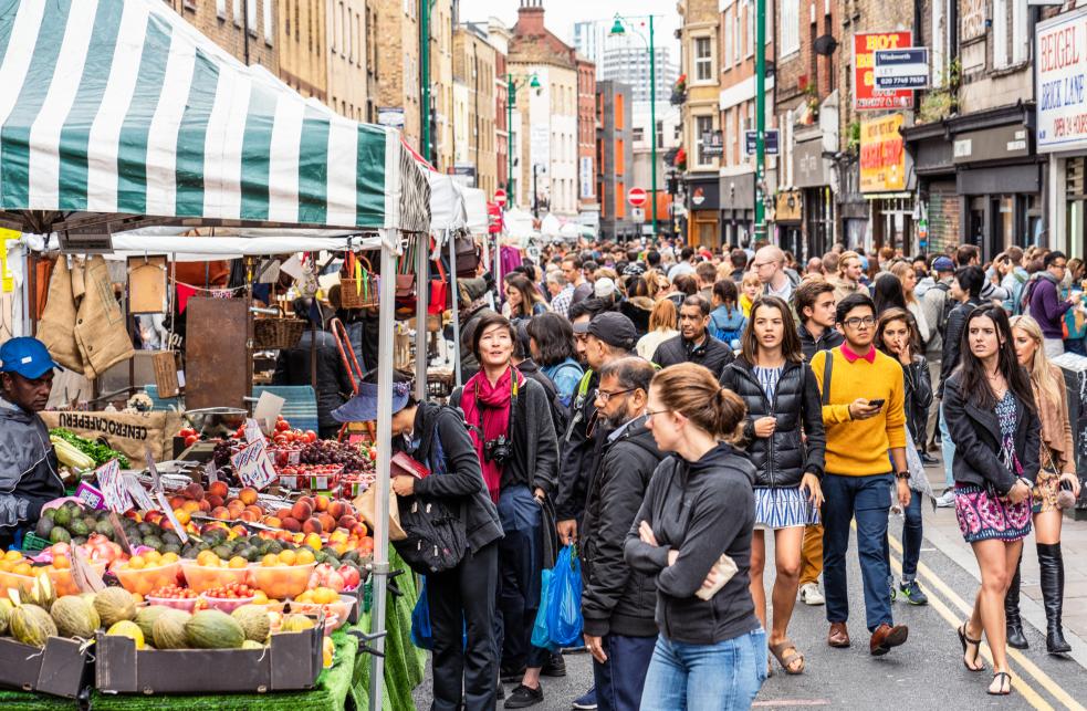 A busy outdoor market with lots of people browsing the stalls