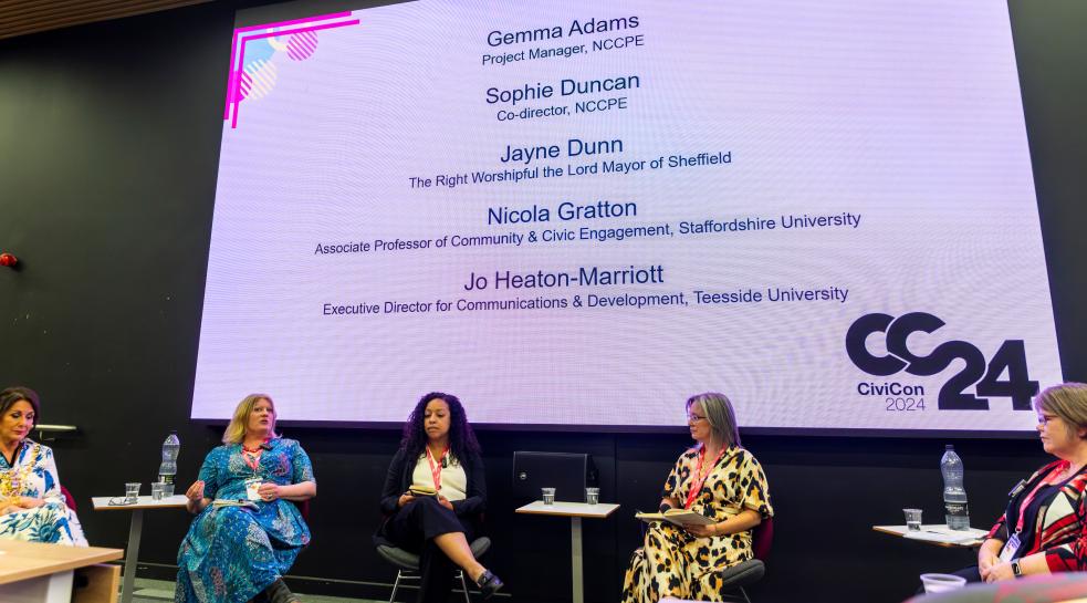 The 5 panel members sitting on chairs on stage for the opening plenary of CiviCon 2024