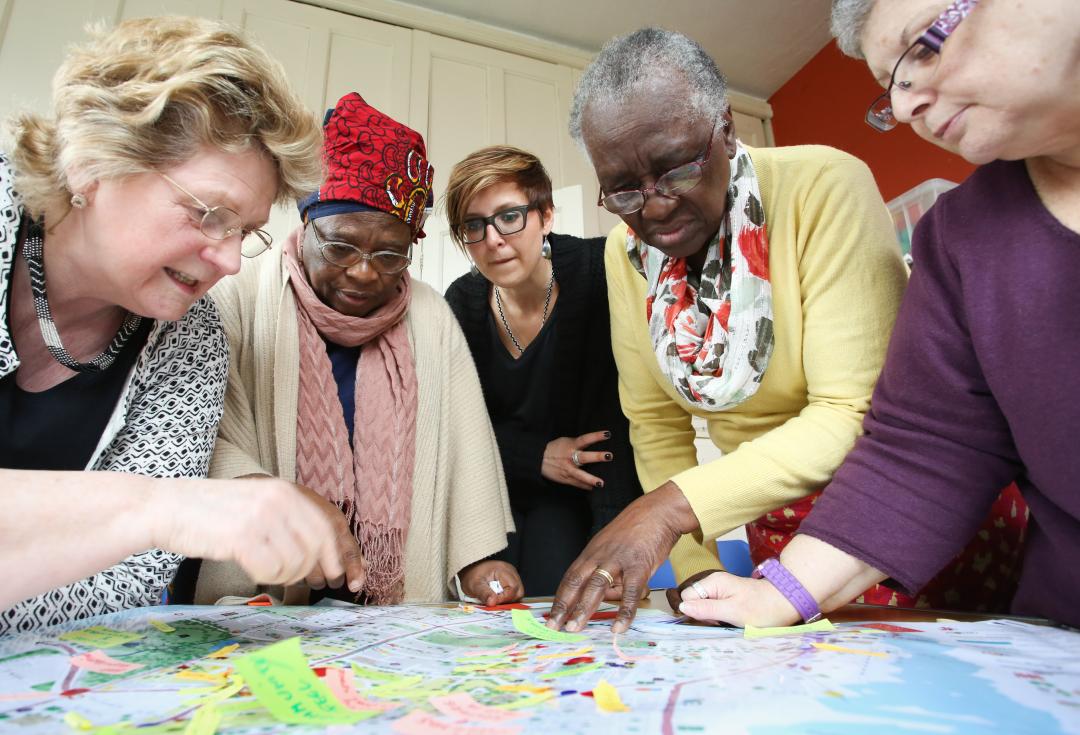An image of a researcher and 4 co-researchers working on a project about age friendly cities