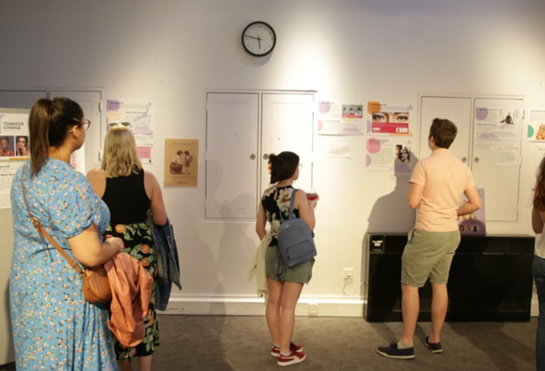 A group of people looking at display boards and posters on a wall
