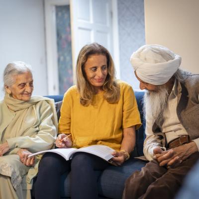 an older man and woman smiling and speaking with a younger woman