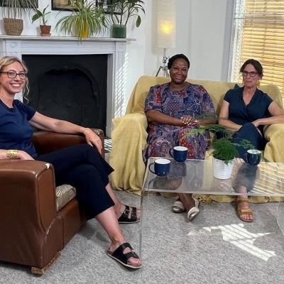 Sophie Duncan, Jude Fransman, Fay Scott, Louise Archer (R-L) sat in armchairs around a coffee table, with filming and sound equipment around them, smiling at the camera
