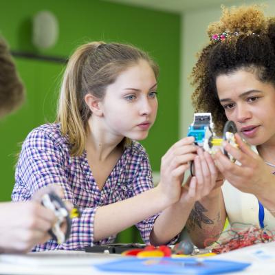 Three young people holding up and looking at circuits