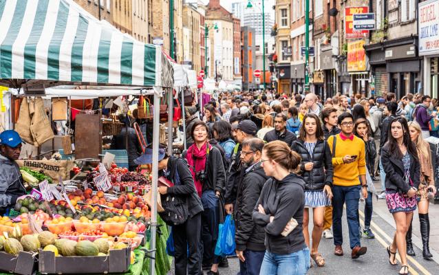 A busy outdoor market with lots of people browsing the stalls