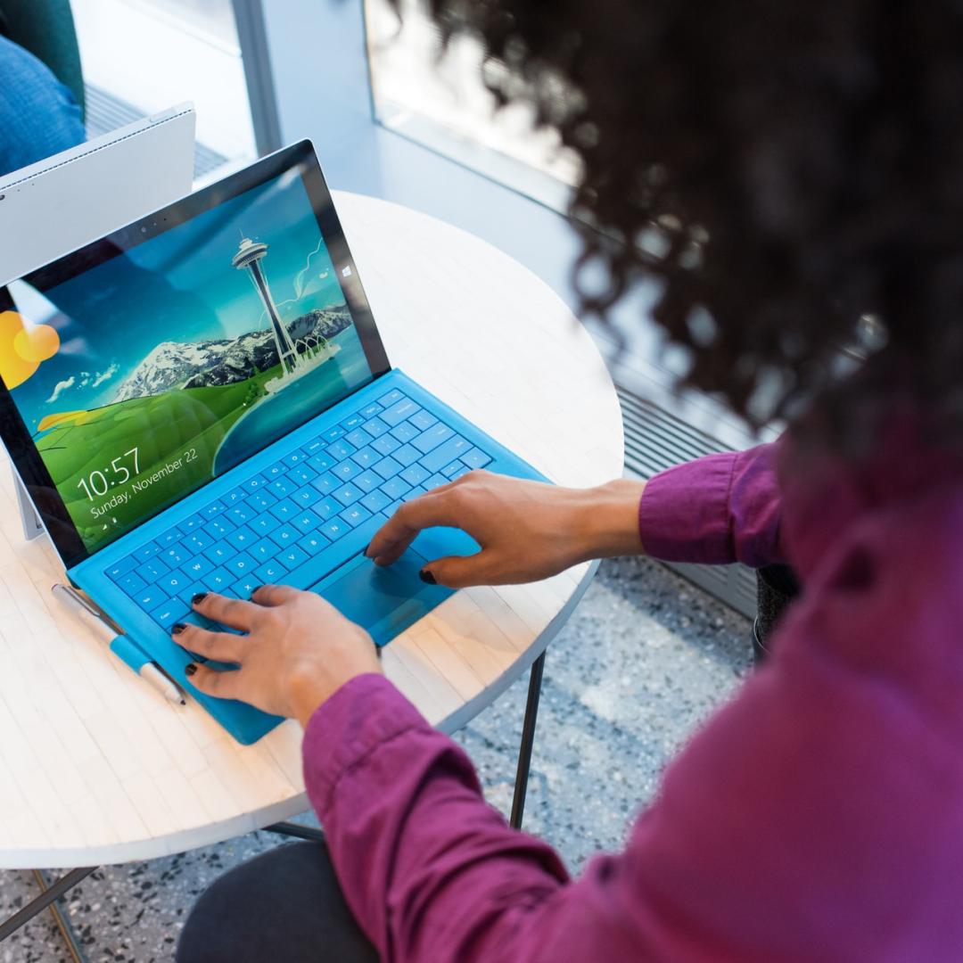 woman in purple jumper on blue laptop